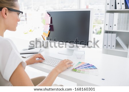 Side view of photo editor working on computer in a bright office