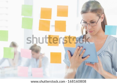 Concentrated female artist with digital tablet and colorful sticky notes at the office