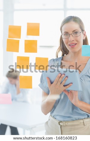 Portrait of a smiling female artist with digital tablet and colorful sticky notes at the office