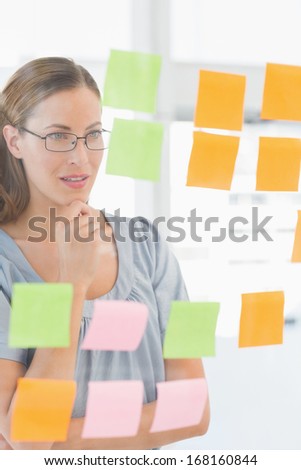 Concentrated female artist looking at colorful sticky notes at the office