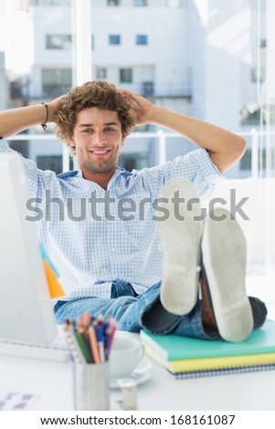 Relaxed casual young business man with legs on desk in a bright office
