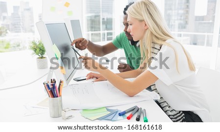 Side view of a casual couple using computer in a bright office