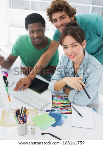 Portrait of three smiling artists working on computer at the office