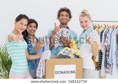 Group of young people with clothes donation gesturing thumbs up