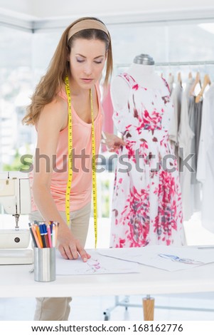 Beautiful female fashion designer working on floral dress at the studio