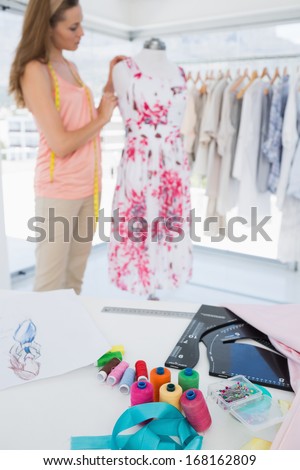 Side view of a beautiful female fashion designer working on floral dress at the studio