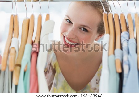 Close-up portrait of happy female customer amid clothes rack
