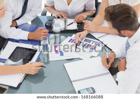 Mid section of young well dressed business people in discussion at a bright office