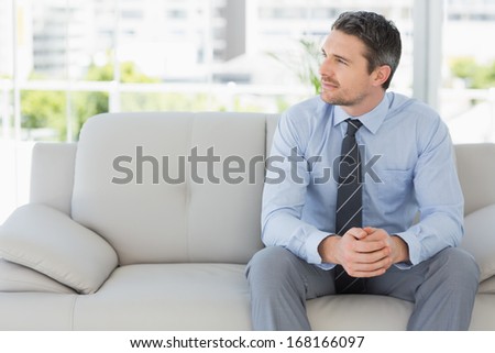 Relaxed well dressed young man sitting on sofa in the house