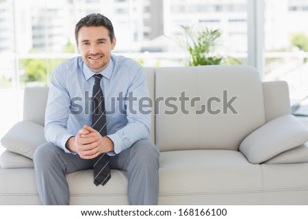 Portrait of a well dressed relaxed young man sitting on sofa in the house