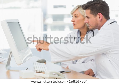 Two concentrated doctors using computer at medical office