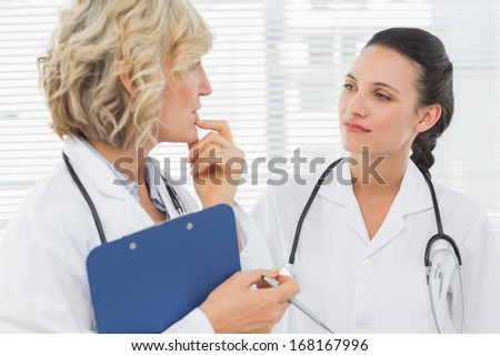Two female doctors with medical reports at the hospital
