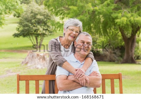 Portrait of a senior woman embracing man from behind at the park