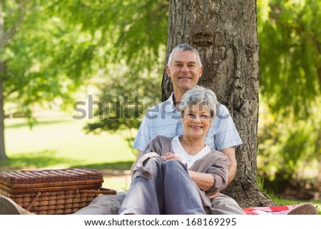 Happy senior man embracing woman from behind at the park