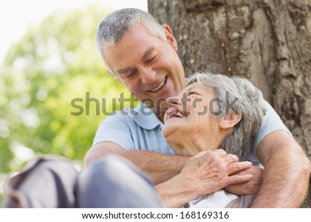 Close-up of a happy senior man embracing woman from behind at the park