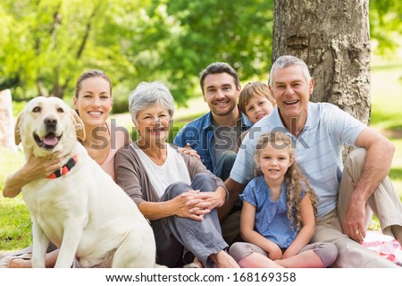 Portrait Of An Extended Family With Their Pet Dog Sitting At The Park