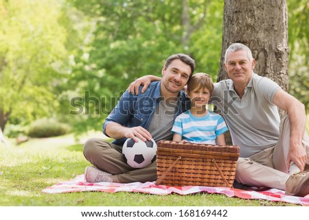 Portrait of grandfather, father and son with picnic basket at the park