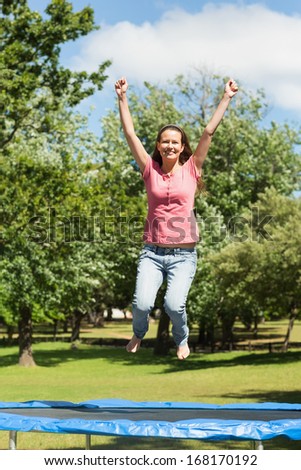 Full length of a happy woman jumping high on trampoline in the park