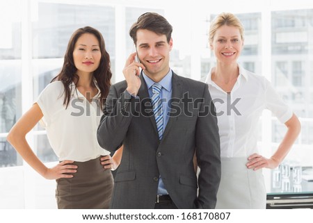 Happy businessman on the phone in front of his team in the office
