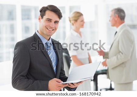 Businessman reading over a document smiling at camera in the office