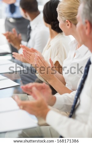 Business people clapping colleague at a meeting in the office