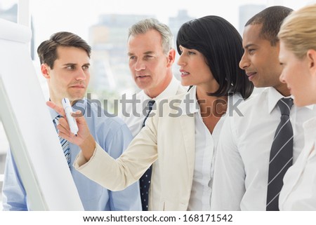 Colleagues Watching Businesswoman Write On Whiteboard In The Office