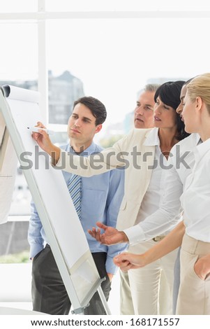 Interested colleagues watching businesswoman writing on whiteboard in the office