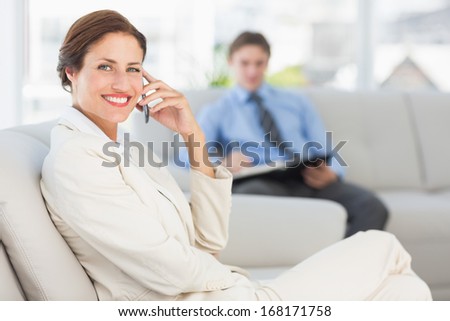 Happy businesswoman on the phone sitting on couch in the office