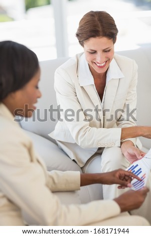 Happy businesswomen meeting to go over figures on the couch in the office