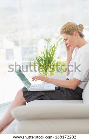 Businesswoman sitting on the couch with laptop in the office
