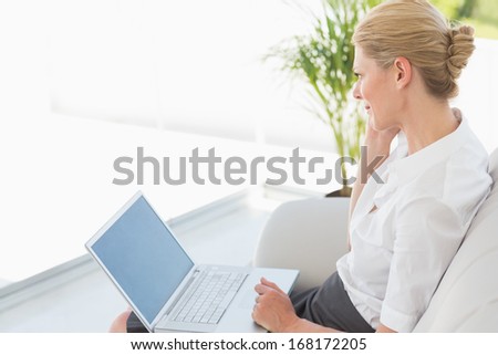 Businesswoman sitting on the couch working on laptop in the office