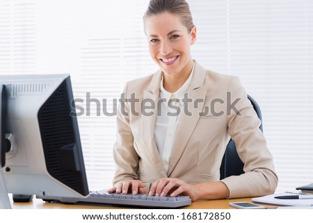 Portrait of a smartly dressed young businesswoman using computer at office desk
