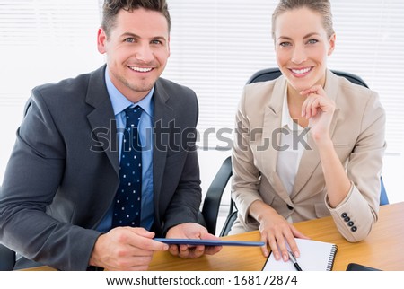 Portrait of a smartly dressed young man and woman in a business meeting at office desk