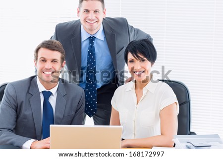 Portrait of smartly dressed young colleagues with laptop at office desk