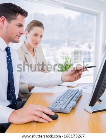 Smartly dressed young man and woman using computer at office desk