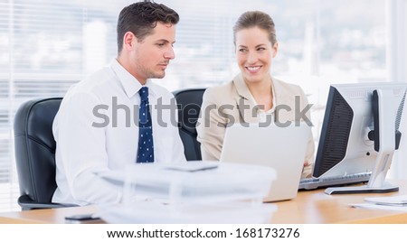 Smartly dressed young man and woman using computer at office desk