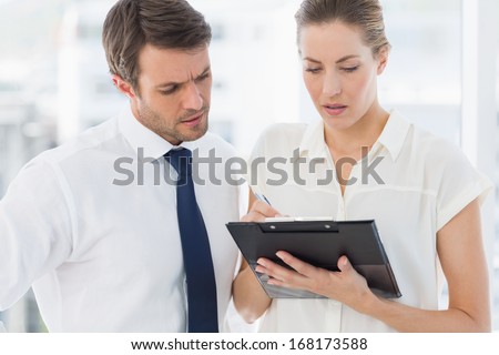 Smartly dressed young man and woman using digital tablet in a bright office