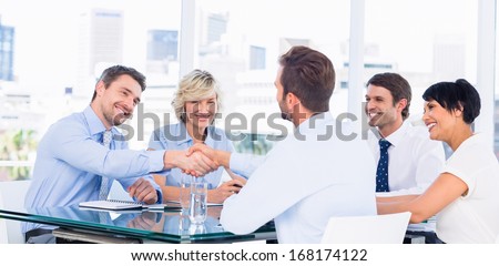 Executives shaking hands during business meeting at office desk