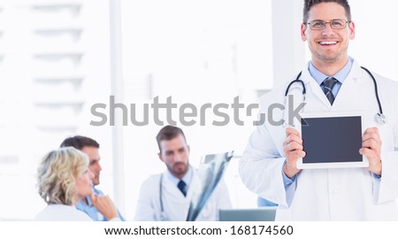 Doctor holding digital tablet with colleagues in meeting at a medical office