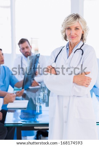 Portrait of a smiling female doctor with colleagues in meeting at a medical office