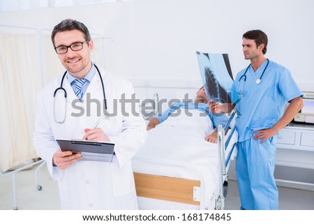 Doctors holding reports by patient in bed at the hospital