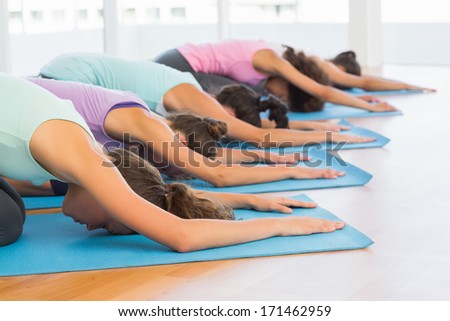 Side view of sporty young women in meditation pose at a bright fitness studio