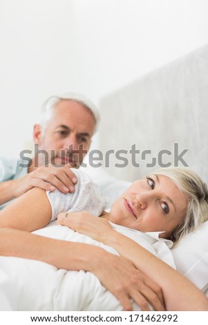 Woman ignoring mature man while lying in bed at the home