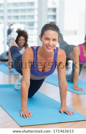 Portrait of smiling young women doing stretching exercises in the fitness studio