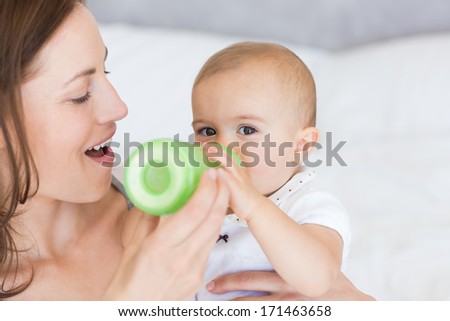 Close-up of a mother feeding baby with milk bottle at home
