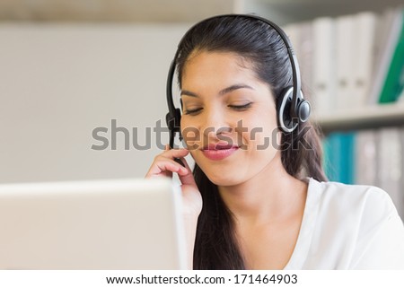Young call center representative using headset in office