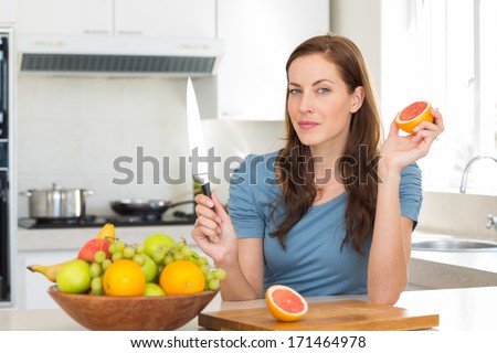 Portrait of a young woman with fruit bowl on counter in the kitchen at home