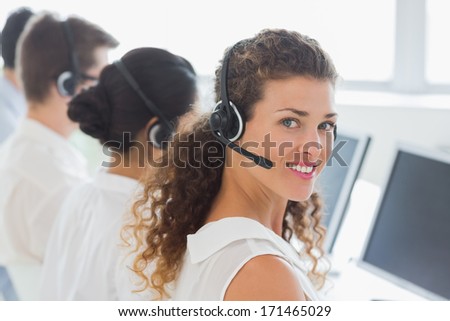 Portrait of beautiful female customer service agent with colleagues working in office