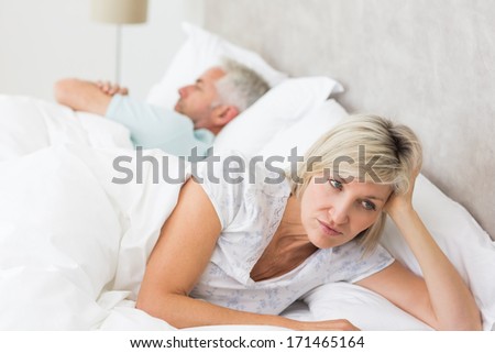 Close-up of a tensed woman lying besides man in bed at home