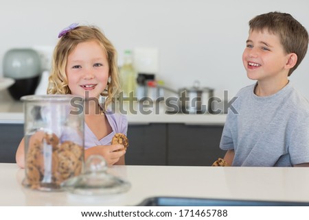 Happy brother and sister having cookies at kitchen counter